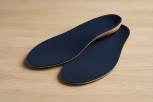 کفی طبی با طراحی ارگونومیک و رنگ تیره، مناسب برای کاهش درد و خستگی در پاها، قرار گرفته بر روی سطح چوبی